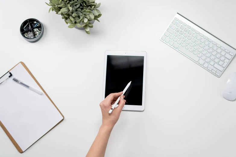 a person holding a pen and writing on a tablet, professional product shot, sleek white, flatlay, background image