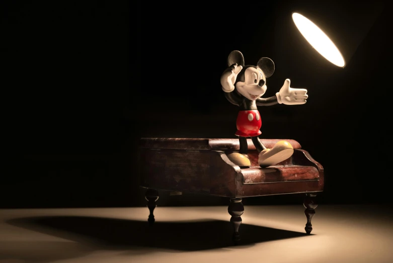 a mickey mouse figurine sitting on top of a chair, an album cover, inspired by Walt Disney, pexels contest winner, movie lighting, playing piano, movie still 8 k, hand