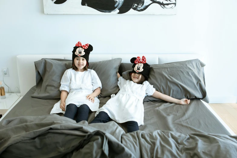 a couple of girls laying on top of a bed, a cartoon, by disney, unsplash, minnie mouse, singapore, official product photo, headpiecehigh quality