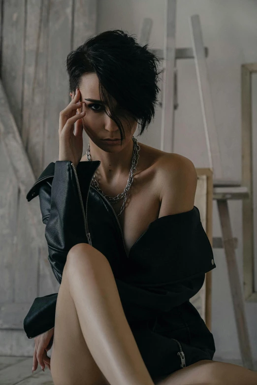 a woman in a black dress sitting on the floor, inspired by Hedi Xandt, trending on pexels, short black hair, wearing a punk outfit, looking her shoulder, androgyny