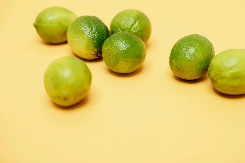 a group of limes sitting on top of a table, by Carey Morris, trending on pexels, on a yellow canva, small chin, green: 0.5, taken with sony alpha 9