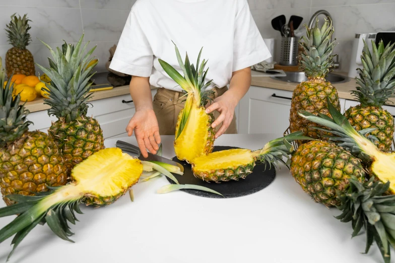 a person cutting up pineapples in a kitchen, by Julia Pishtar, plating, fan favorite, product introduction photo, half image