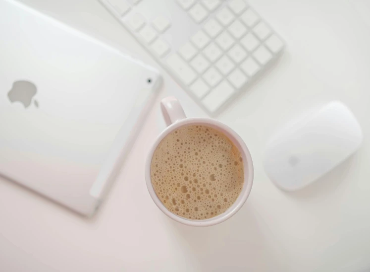 a cup of coffee next to a keyboard and mouse, pexels, cream and white color scheme, rectangle, white table, milk