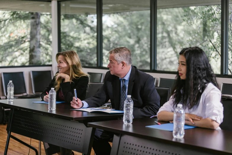 a group of people sitting around a table, sitting on a desk