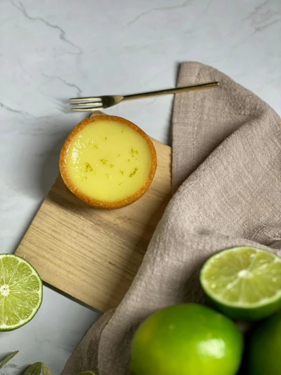a piece of pie sitting on top of a cutting board next to limes, a picture, flan, detailed product image, lime and gold hue, full face view