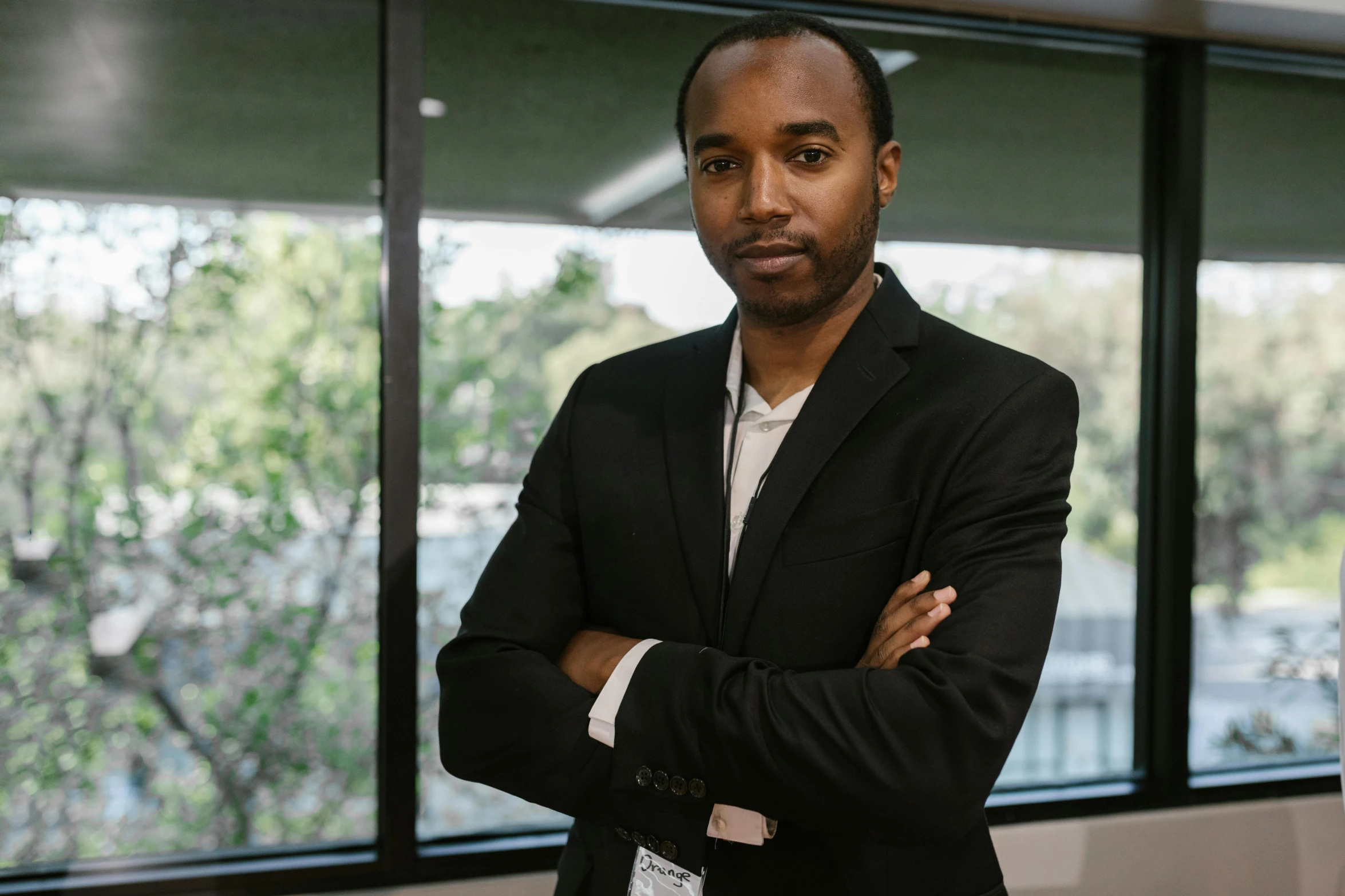 a man in a suit standing in front of a window, by Jeffrey Smith, hurufiyya, dark-skinned, ai researcher, african aaron paul, serious focussed look