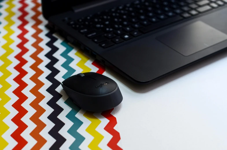 a laptop computer sitting on top of a desk next to a mouse, by Julia Pishtar, unsplash, computer art, multi - coloured, matte black paper, computer mouse, subtle pattern