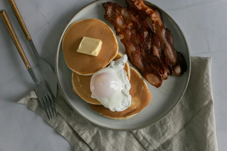 a white plate topped with pancakes and bacon, a portrait, unsplash, eggs, classic gem, loyal, smokey