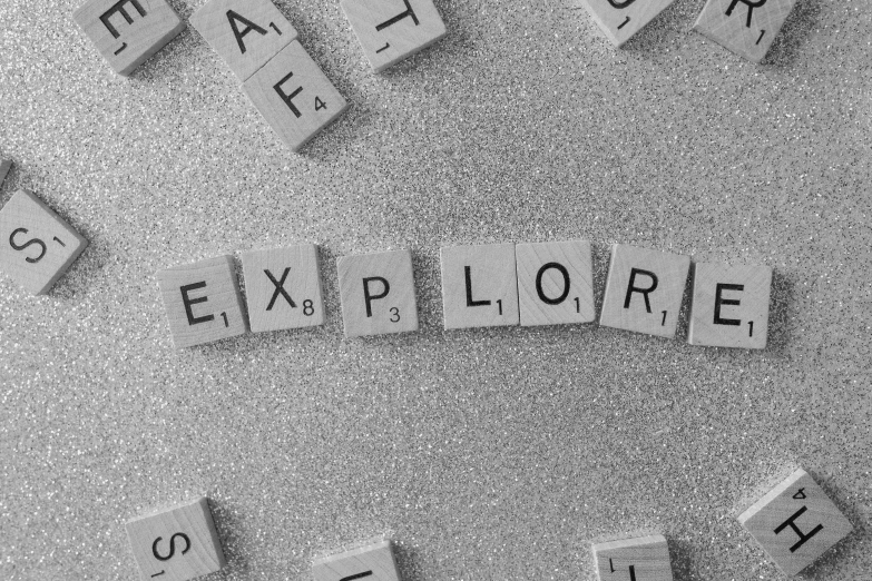 a black and white photo of the word explore spelled in scrabbles, pexels, analytical art, sparkle, explorers, grey colours, devon cady-lee