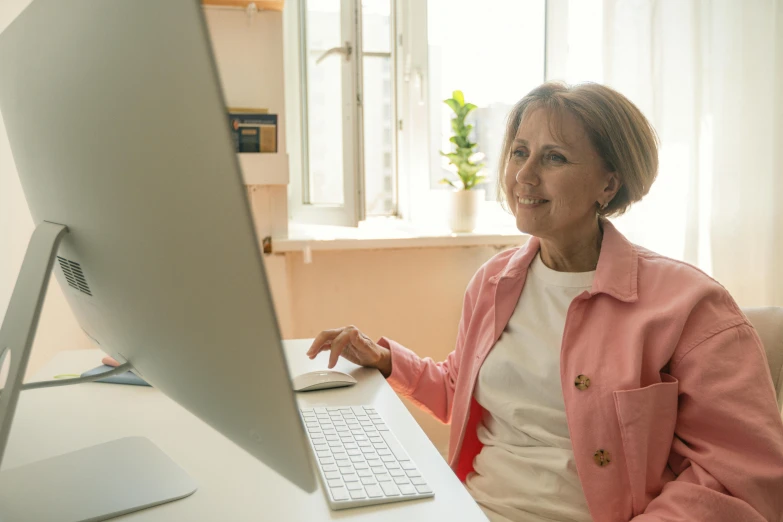 a woman sitting at a desk in front of a computer, pexels contest winner, middle aged, health supporter, profile image, bottom angle