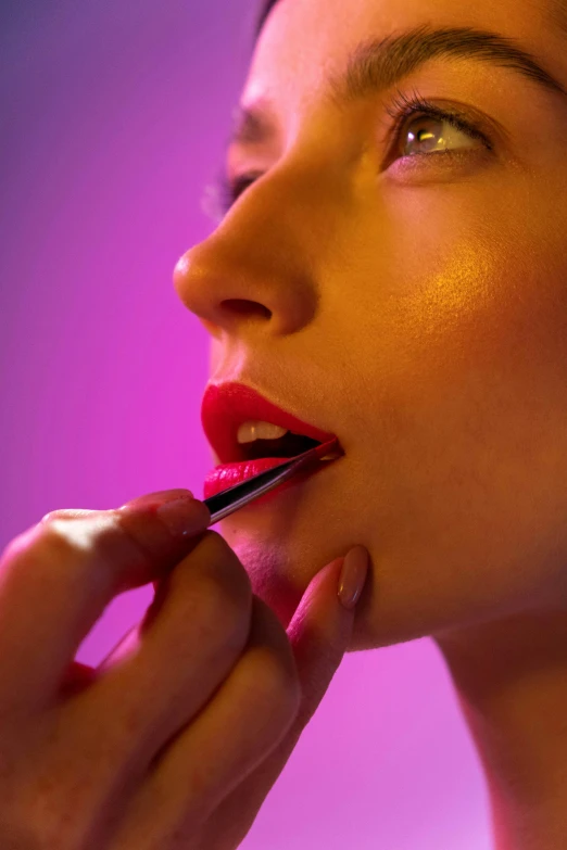 a woman is putting lipstick on her lips, inspired by Nan Goldin, photorealism, colorized neon lights, premium, bright vivid color hues:1, makeup