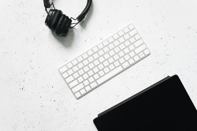 a white desk topped with a keyboard and headphones, trending on pexels, silver accessories, background image, white tile on the floor, item