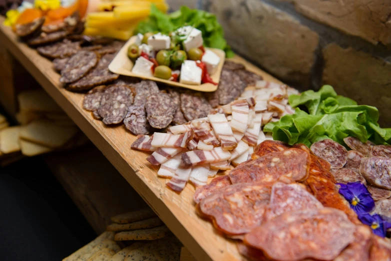 a table topped with lots of different types of food, by Daniel Lieske, pexels contest winner, salami, profile image, waist up, on a wooden tray