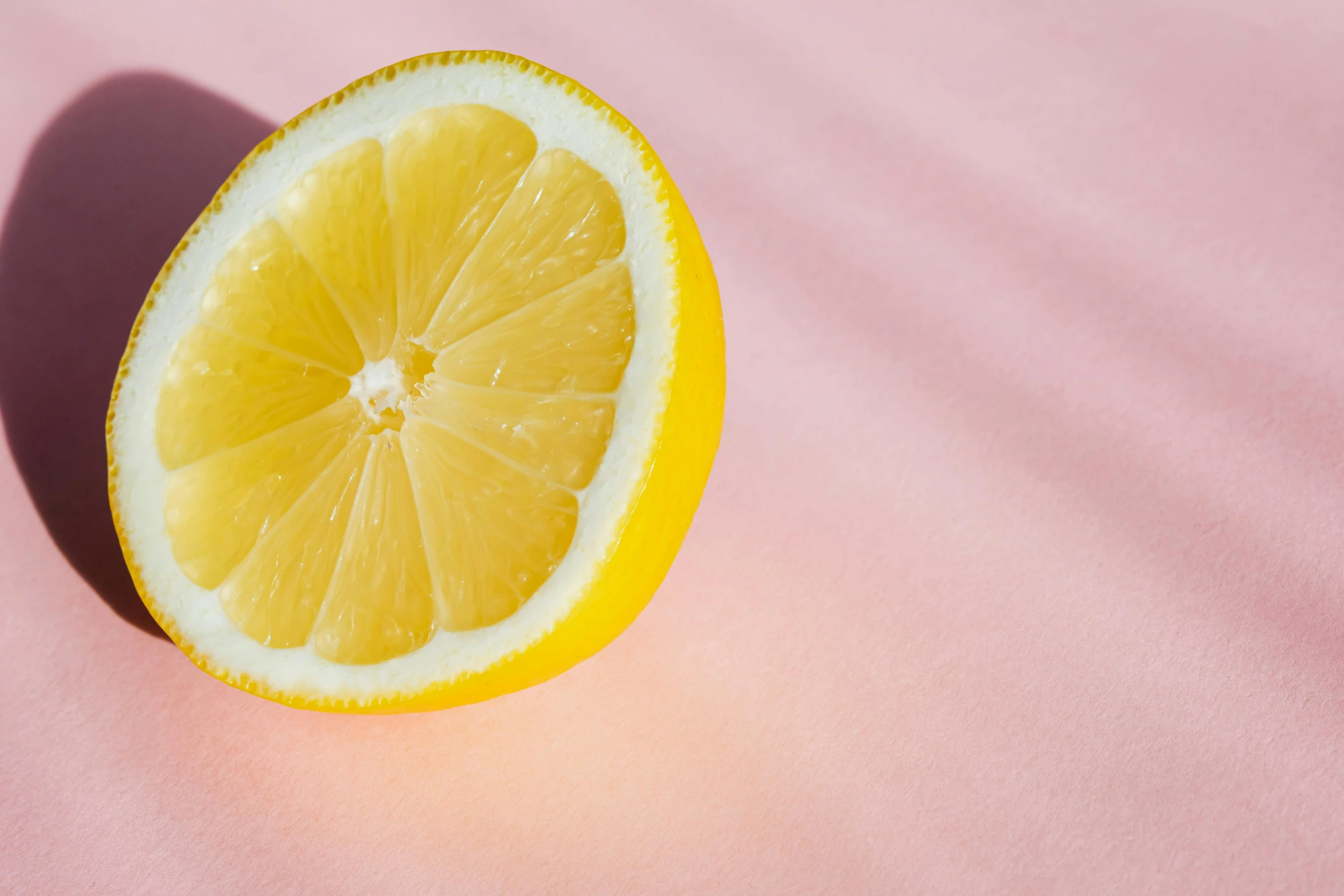 a half of a lemon on a pink surface, by Carey Morris, trending on pexels, recipe, pale yellow wallpaper, colors: yellow, lecherous pose