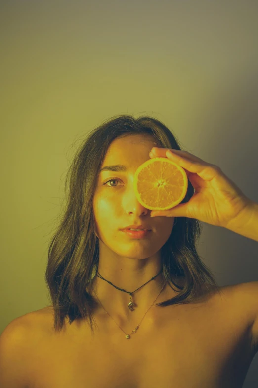 a woman holding an orange in front of her face, inspired by Elsa Bleda, pexels contest winner, wearing a lemon, orthochromatic look filter, dua lipa, profile image