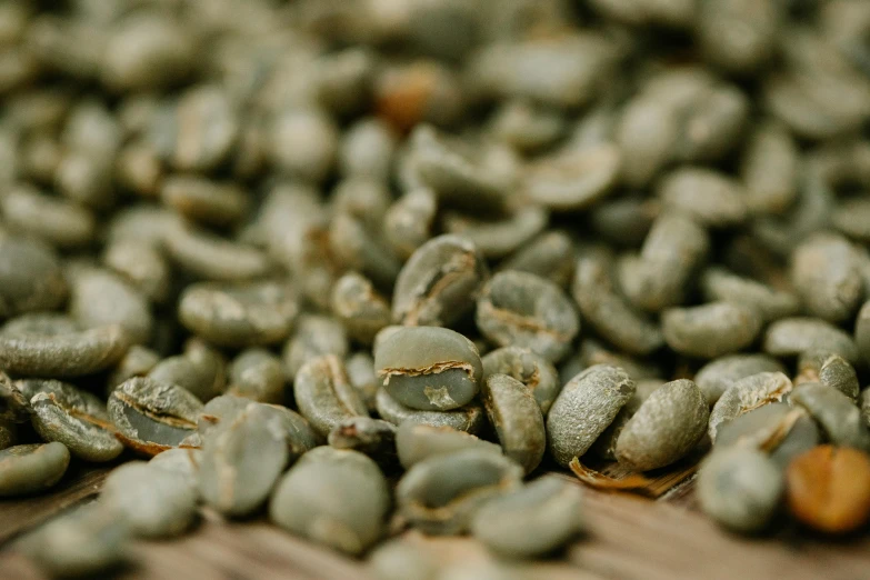 a pile of green coffee beans sitting on top of a wooden table, a macro photograph, by Emma Andijewska, trending on unsplash, background image, detailed product image, zoomed out to show entire image, thumbnail