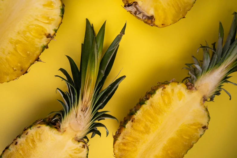 a group of pineapples cut in half on a yellow surface, trending on unsplash, background image