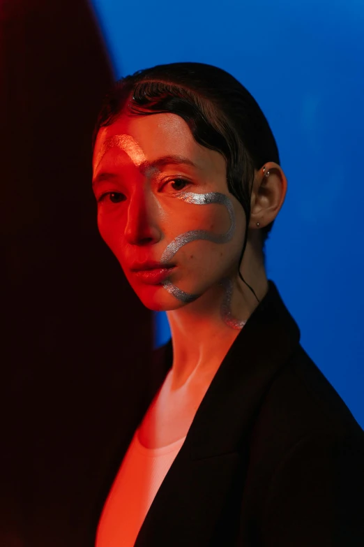 a woman standing in front of a red light, an album cover, inspired by Taro Yamamoto, trending on pexels, hyperrealism, blue holographic face, attractive androgynous humanoid, portrait made of paint, dark. studio lighting