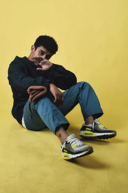 a man sitting on top of a yellow floor, by Niko Henrichon, instagram, nike air max, jayison devadas style, headshot profile picture, jean and multicolor shoes