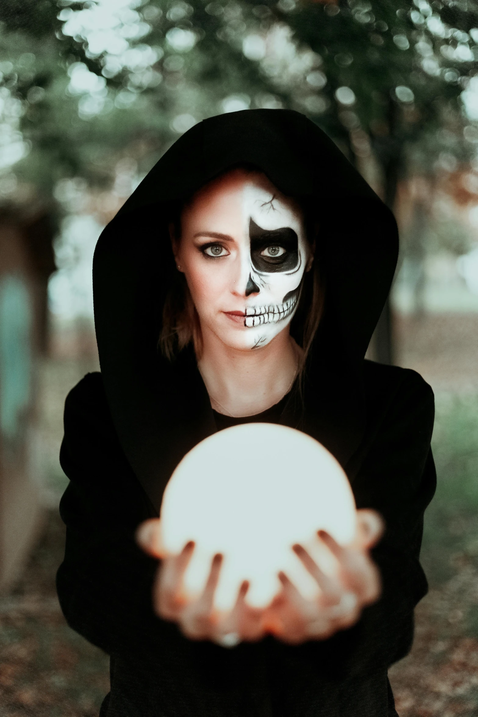 a woman in a black hoodie holding a white ball, pexels contest winner, realism, skeleton face symmetrical face, dressed as an oracle, skeleton in a suit, unknown zodiac sign