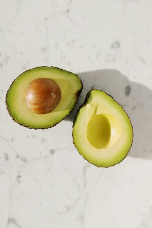 an avocado cut in half on a table, trending on pexels, hyperrealism, smooth marble surfaces, avatar image, 6 pack, gold