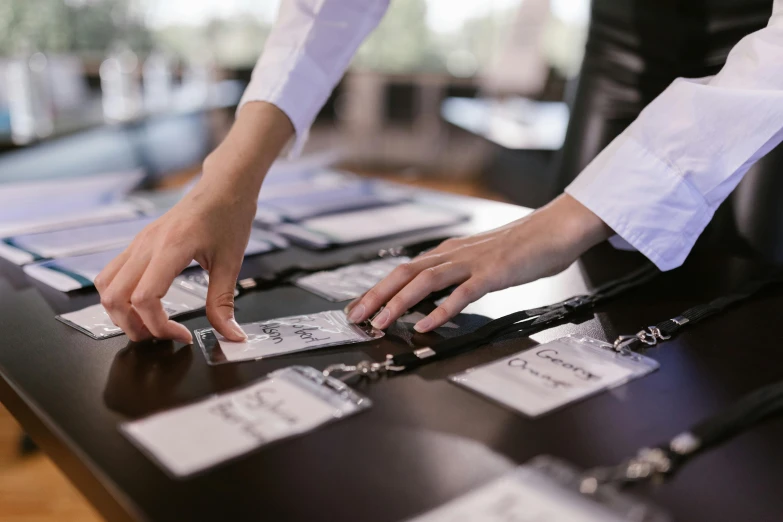 a close up of a person's hands on a table, pair of keycards on table, in a row, business surrounding, long table