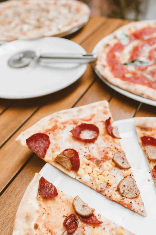 a pizza sitting on top of a white plate on top of a wooden table, thumbnail, splento, different sizes, up-close