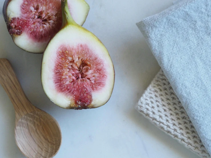 a couple of figs sitting on top of a table, inspired by Jane Nasmyth, unsplash, private press, kitchen background, background image, lined in cotton, sustainable materials