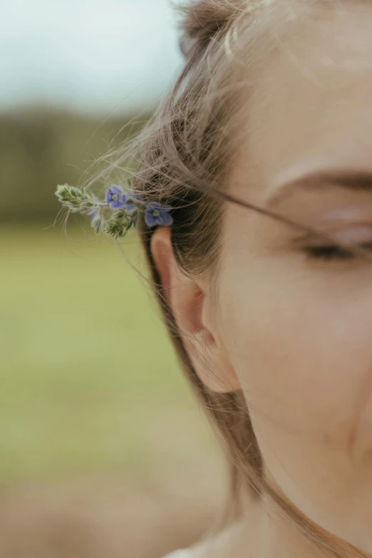 a close up of a woman with a flower in her hair, by Niko Henrichon, unsplash, blue flowers accents, sideburns, zoomed out view, low quality photo