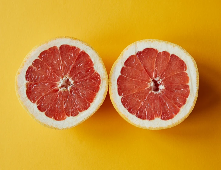 two halves of grapefruit on a yellow background, by Carey Morris, trending on pexels, on a gray background, bright colors with red hues, pictured from the shoulders up, highly intricate