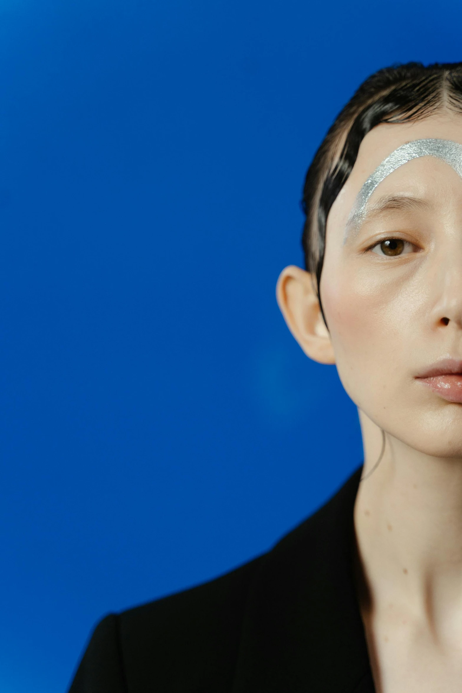 a woman standing in front of a blue background, an album cover, inspired by Gao Cen, hyperrealism, white skin and reflective eyes, araki, close - up studio photo, highlight