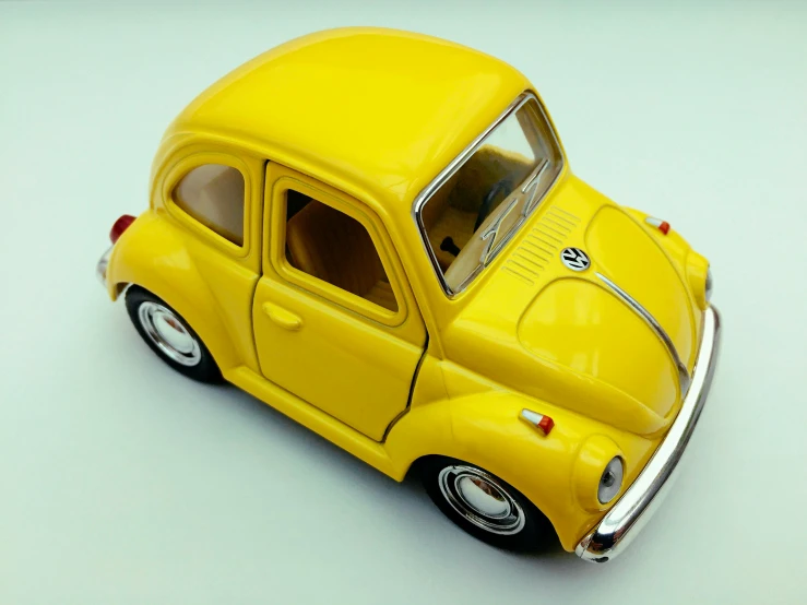 a yellow toy car on a white surface, a picture, unsplash, photorealism, beetle, posable pvc, y2k”, vintage!