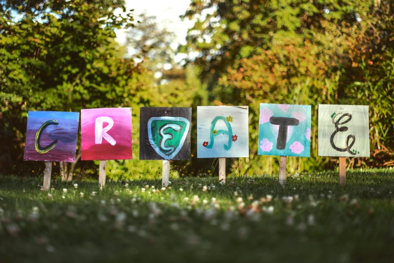 a row of colorful signs sitting on top of a lush green field, by Dirk Crabeth, graffiti, symbol for the word ersatz, greta thunberg, avatar image, parade