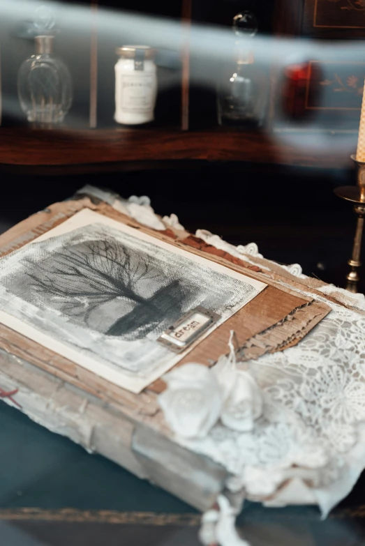 a book sitting on top of a table next to a candle, inspired by Hedda Sterne, process art, faded parchment, stunning large format photograph, lace, rustic