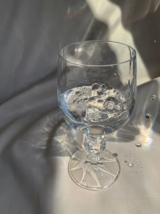 a glass of water sitting on top of a table, a photorealistic painting, by Ryan Pancoast, unsplash, photorealism, ethereal bubbles, stippled light, maia sandu hyperrealistic, taken on iphone 14 pro