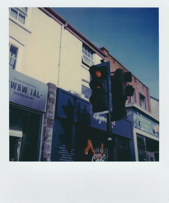 a traffic light sitting on the side of a road, a polaroid photo, by Nick Fudge, happening, shopwindows, clear blue skies, taken from the high street, alternate album cover