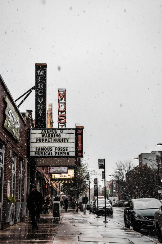 a theater sign sitting on the side of a road, a picture, by Dan Frazier, unsplash contest winner, city snowing with a lot of snow, thumbnail, low quality photo, buildings