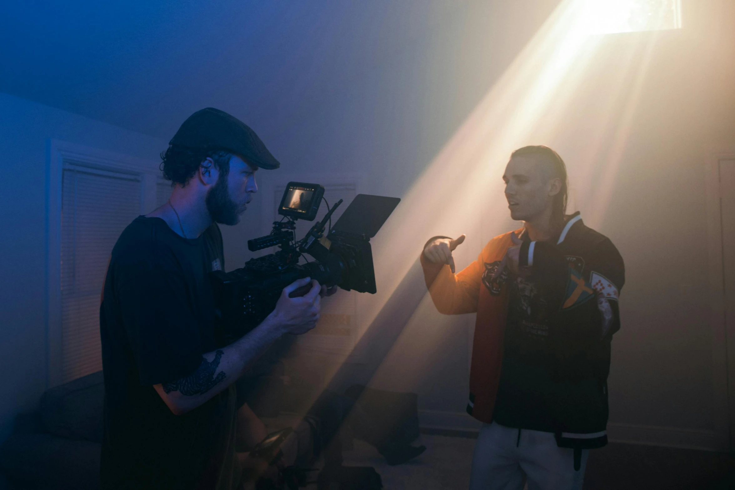 a man standing next to another man holding a camera, surrounding cinematic light, performing a music video, charli bowater and artgeem, ray lighting from top of frame