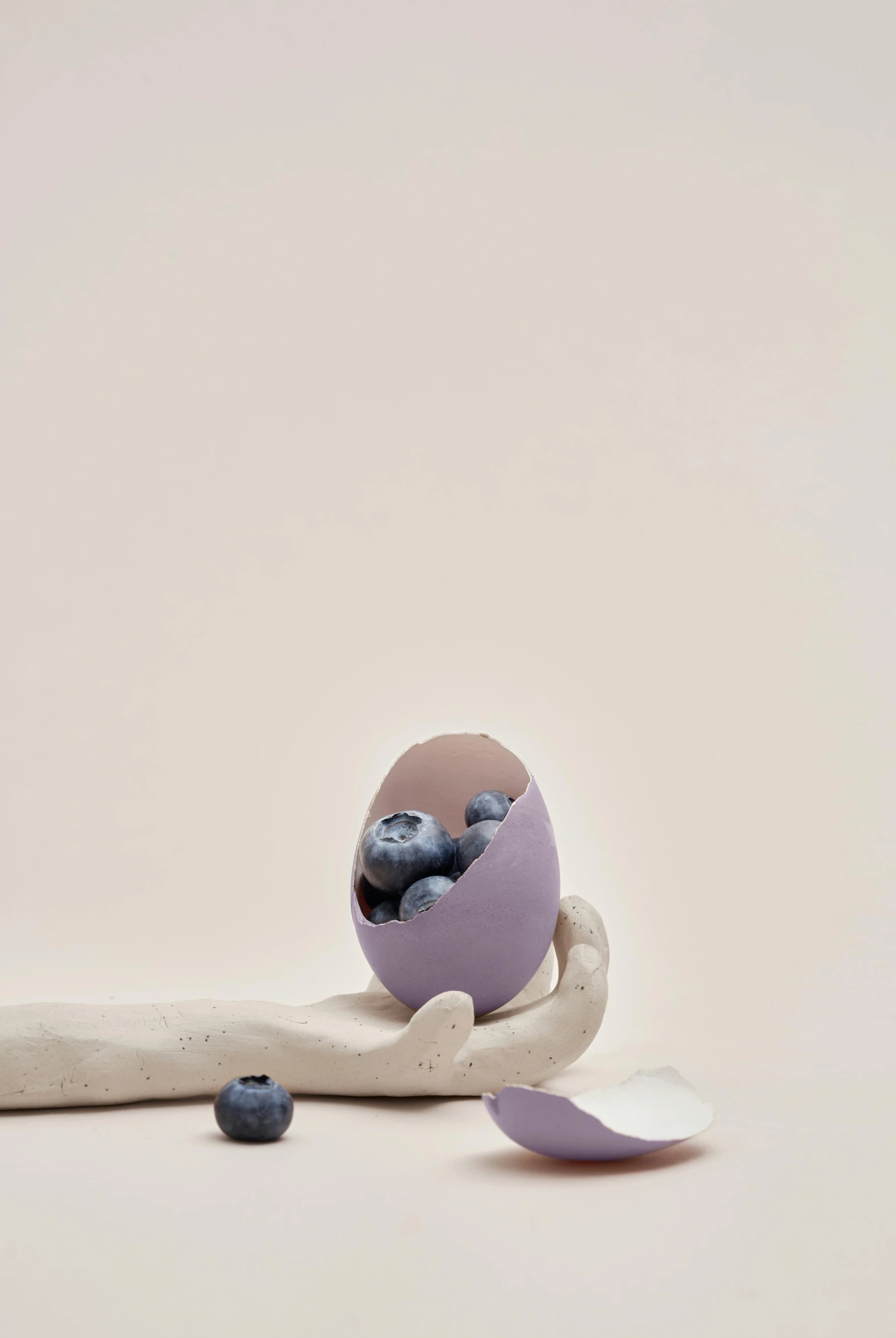 a purple egg sitting on top of a white table, by Georgina Hunt, trending on pexels, conceptual art, berries inside structure, clay render, hand, hero shot