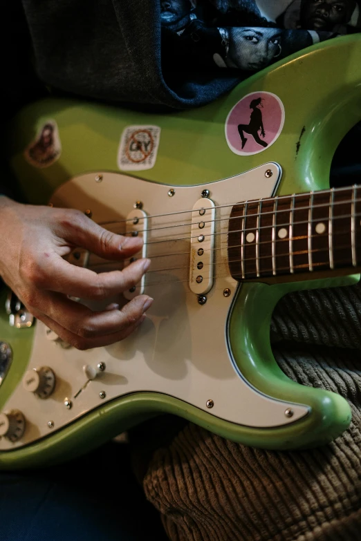 a close up of a person playing a guitar, an album cover, flickr, fender stratocaster, green and purple, photograph credit: ap, promo image