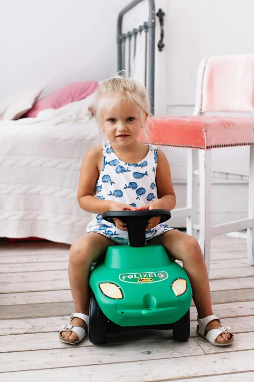 a little girl sitting on top of a green toy car, inspired by Harry Haenigsen, walking towards the camera, jajaboonords flipjimtots, hero shot, banner