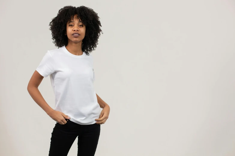 a woman standing with her hands in her pockets, trending on unsplash, happening, white tshirt, official product photo, looking off to the side, full product shot