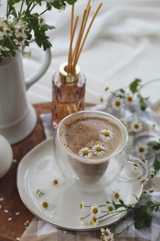 a cup of coffee sitting on top of a wooden tray, flowers and stems, chamomile, milk and mocha style, sparkling