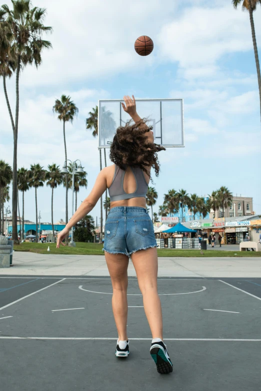 a woman standing on top of a basketball court holding a basketball, unsplash contest winner, happening, wearing denim short shorts, santa monica beach, in a jumping float pose, chloe bennet