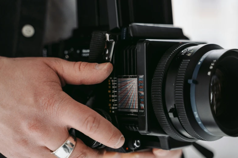 a close up of a person holding a camera, unsplash, photorealism, cinestill hasselblad 8 5 mm, hd footage, 1970s cinema camera, behind the scenes photo