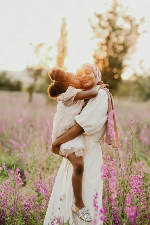 a woman holding a child in a field of flowers, pexels contest winner, light skinned african young girl, holding each other, instagram post, lush surroundings