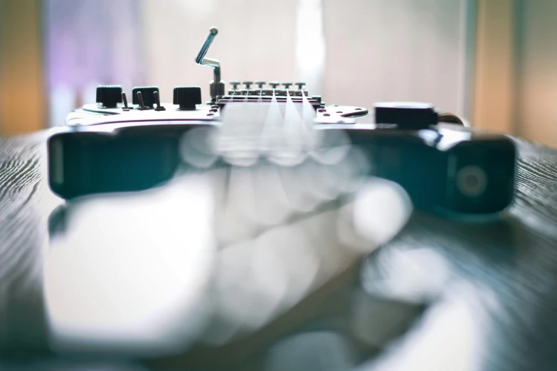 a guitar sitting on top of a wooden table, by David Donaldson, unsplash, light and space, tiltshift, synthesizers, bending down slightly, instagram picture