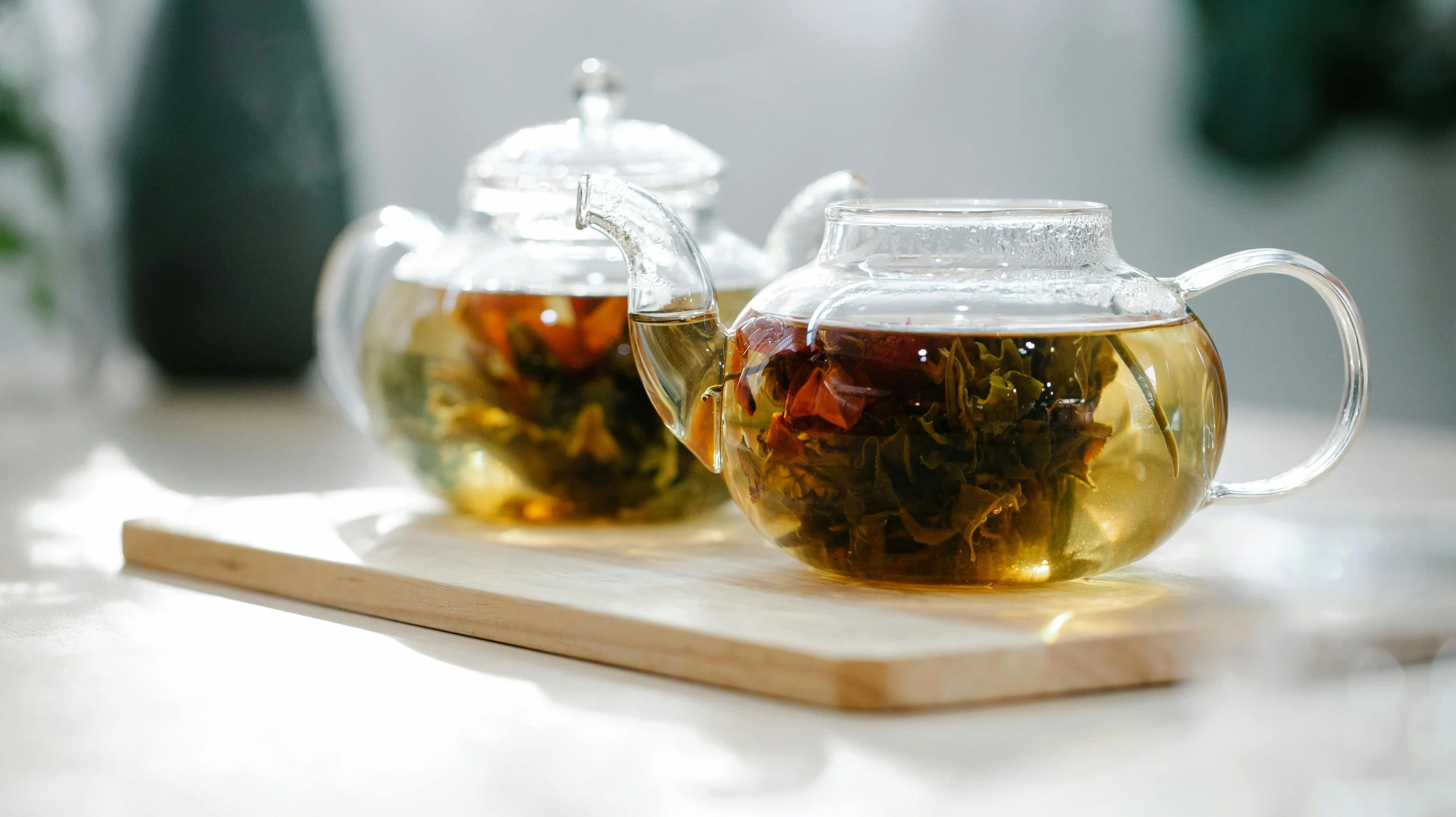 a tea pot filled with green tea sitting on top of a wooden tray, inspired by Cui Bai, pexels, plants in glasses, white, jasmine, partially submerged