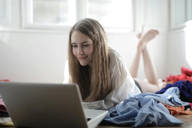 a woman laying on the floor using a laptop, trending on pexels, pale-skinned, someone sits in bed, looking across the shoulder, lightly dressed