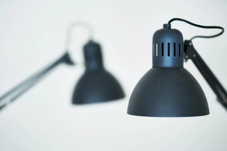 a couple of black lamps sitting on top of a table, unsplash, photorealism, wall torches, blue, commercial photo, grey